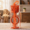 Orange decorative item in clear packaging on a wooden table with a blurred indoor background
