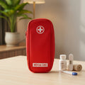 Red medical case with a cross symbol on a wooden surface with medical supplies.