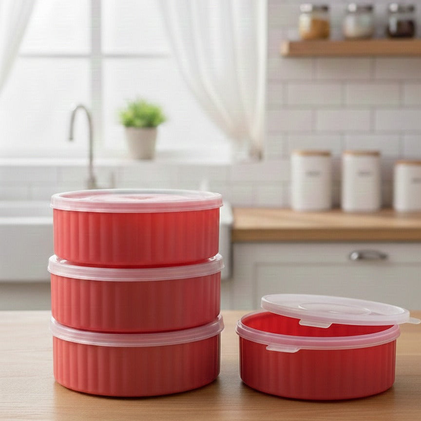 Set of red food storage containers on a kitchen counter with a window and shelves in the background.
