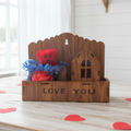 Wooden box with 'LOVE YOU' text, red teddy bear, and blue flowers on a light wooden surface.