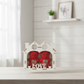 Red heart-shaped boxes in a decorative white box on a light wooden surface with a blurred background.
