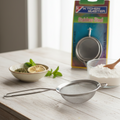 Metal strainer on a kitchen counter with a box labeled 'Kitchen Master' in the background.
